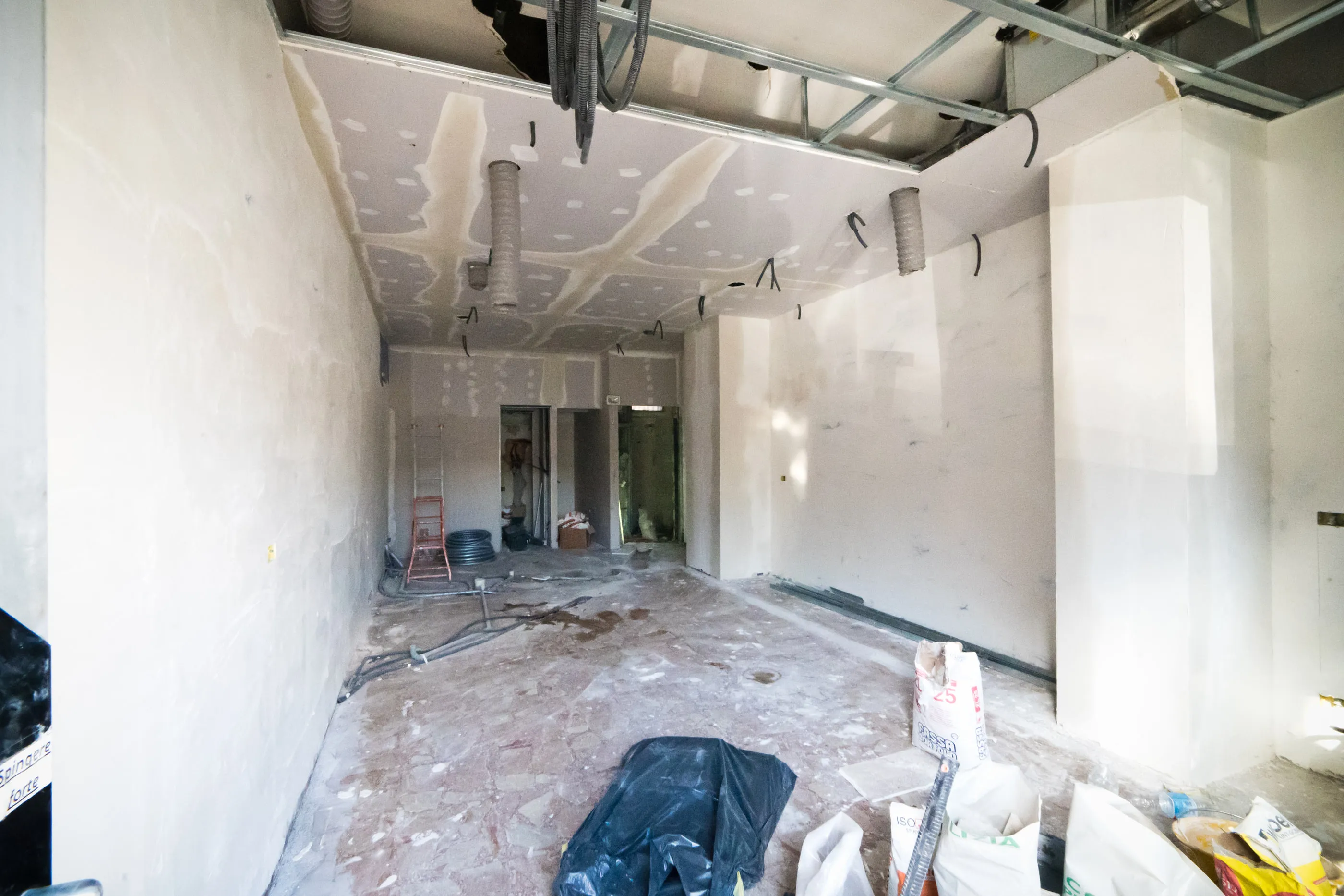 Cantiere di un locale commerciale con controsoffitto in cartongesso e canalizzazioni degli impianti in corso di posa