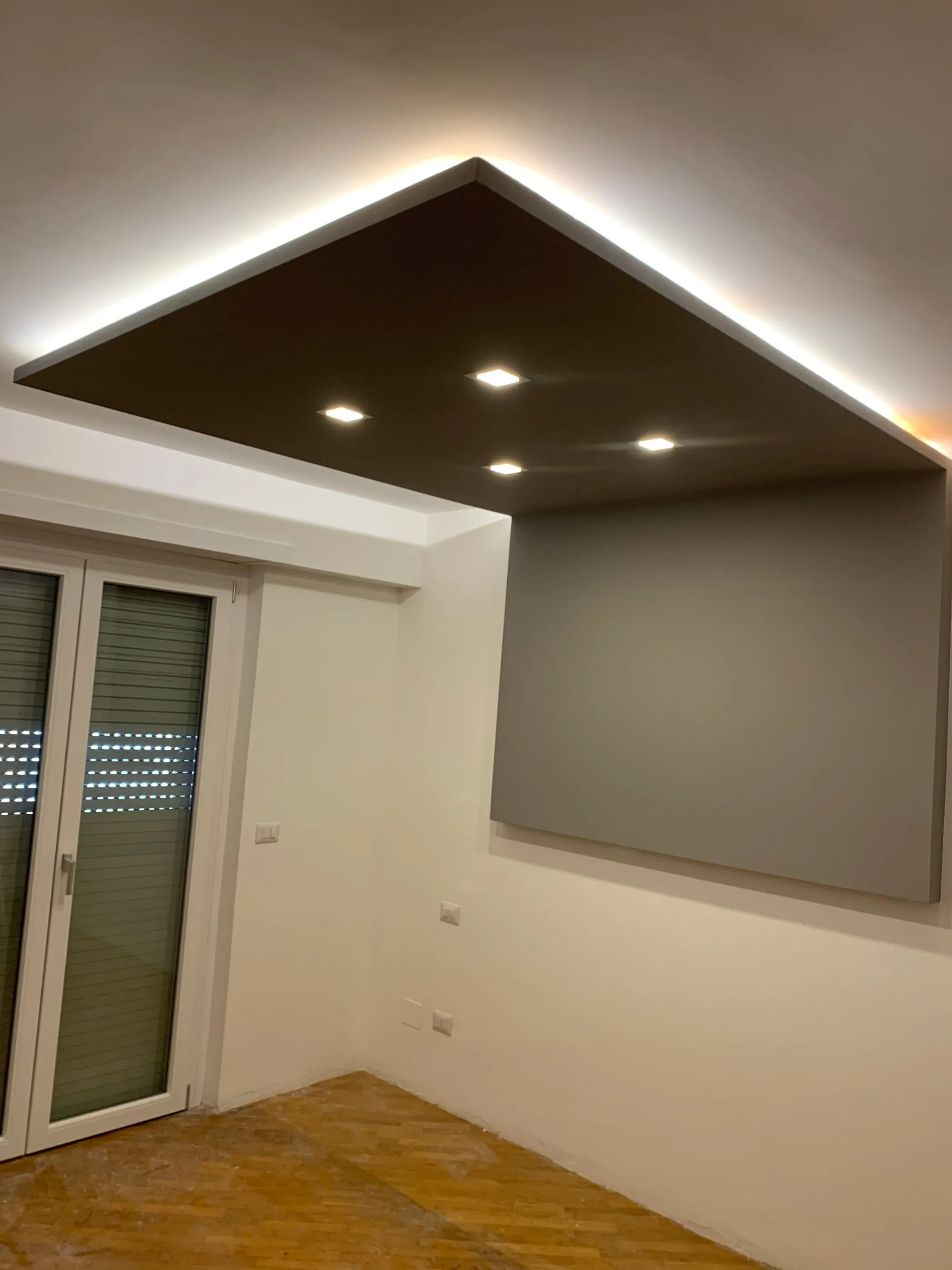 Controsoffitto in cartongesso color tortora con faretti incassati e luce perimetrale nascosta, sopra una finestra a due ante
