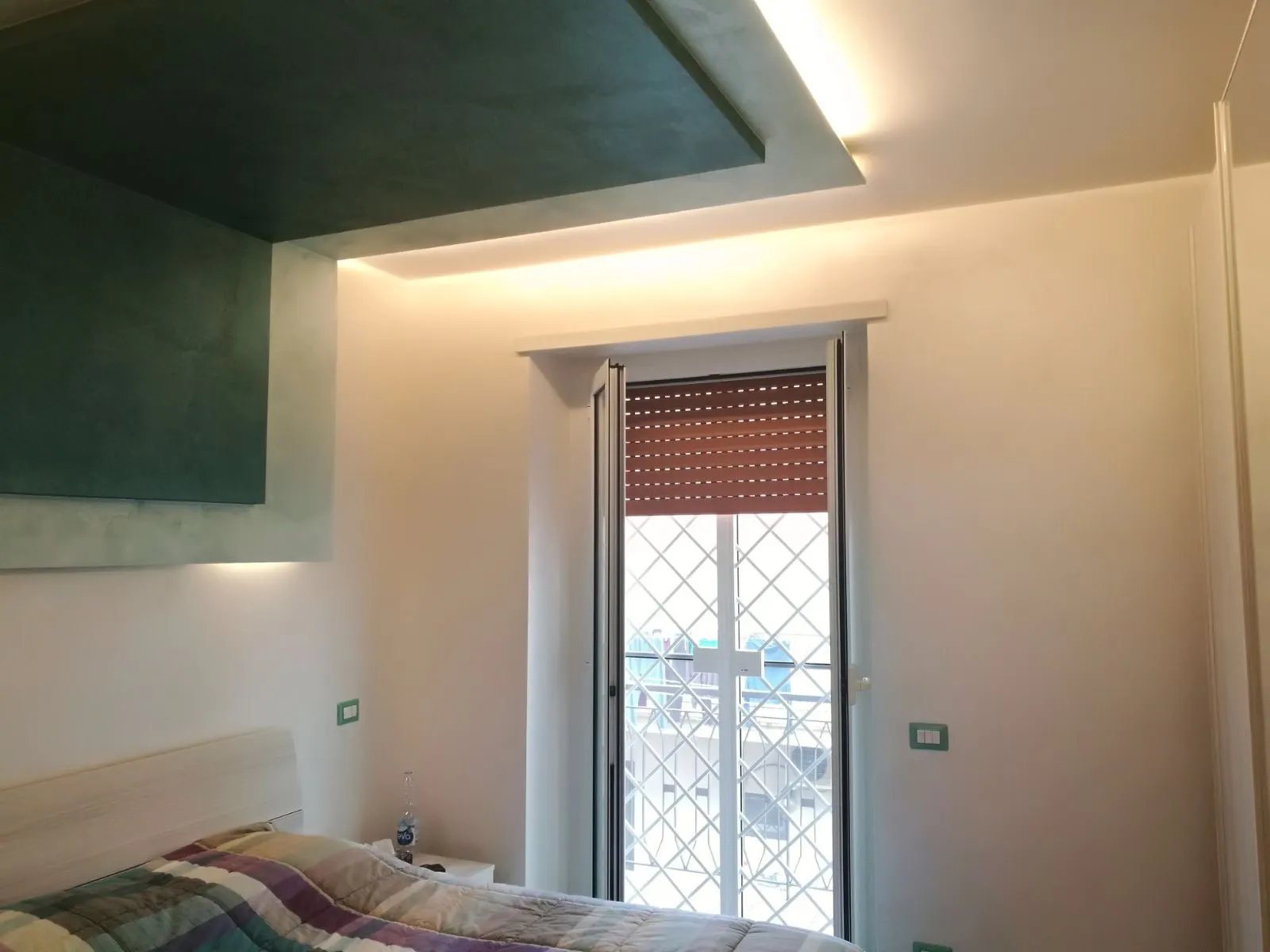 Camera da letto con controsoffitto in cartongesso con velatura verde e luce diffusa lungo il bordo