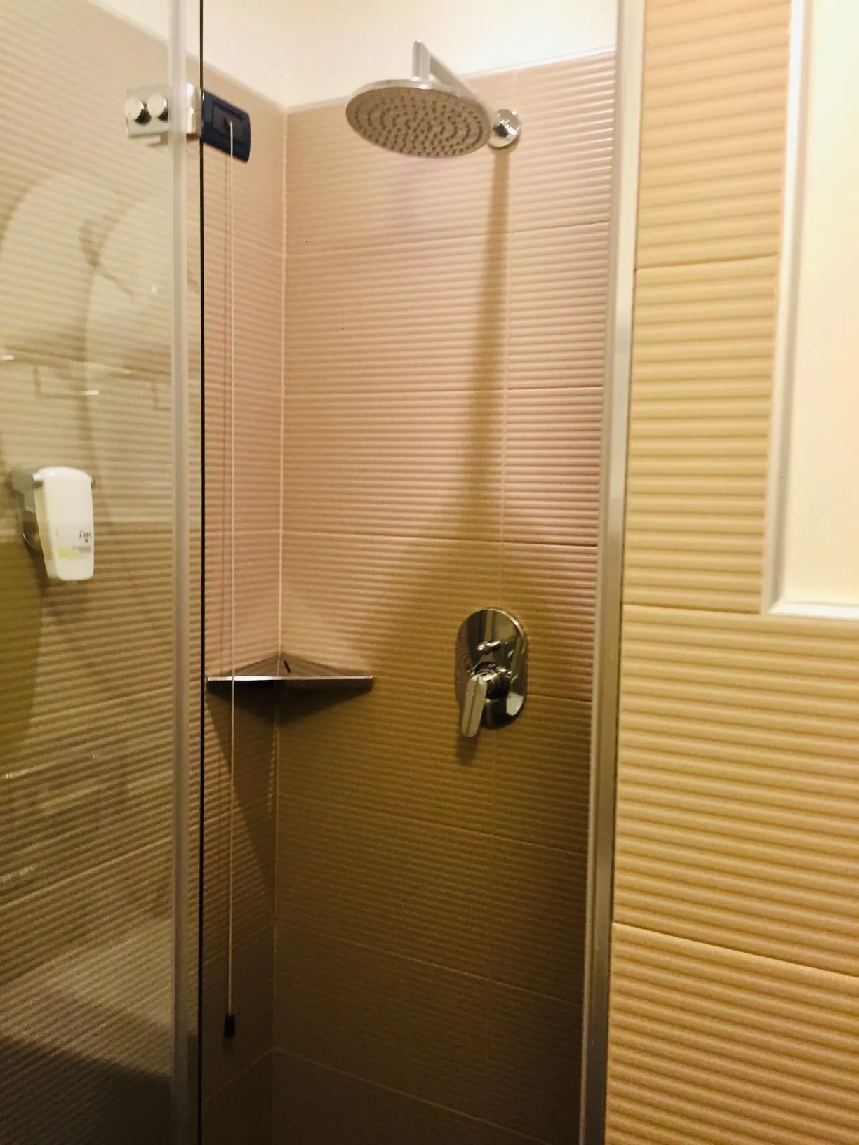 Doccia con soffione a pioggia, miscelatore cromato e rivestimento beige a rilievo