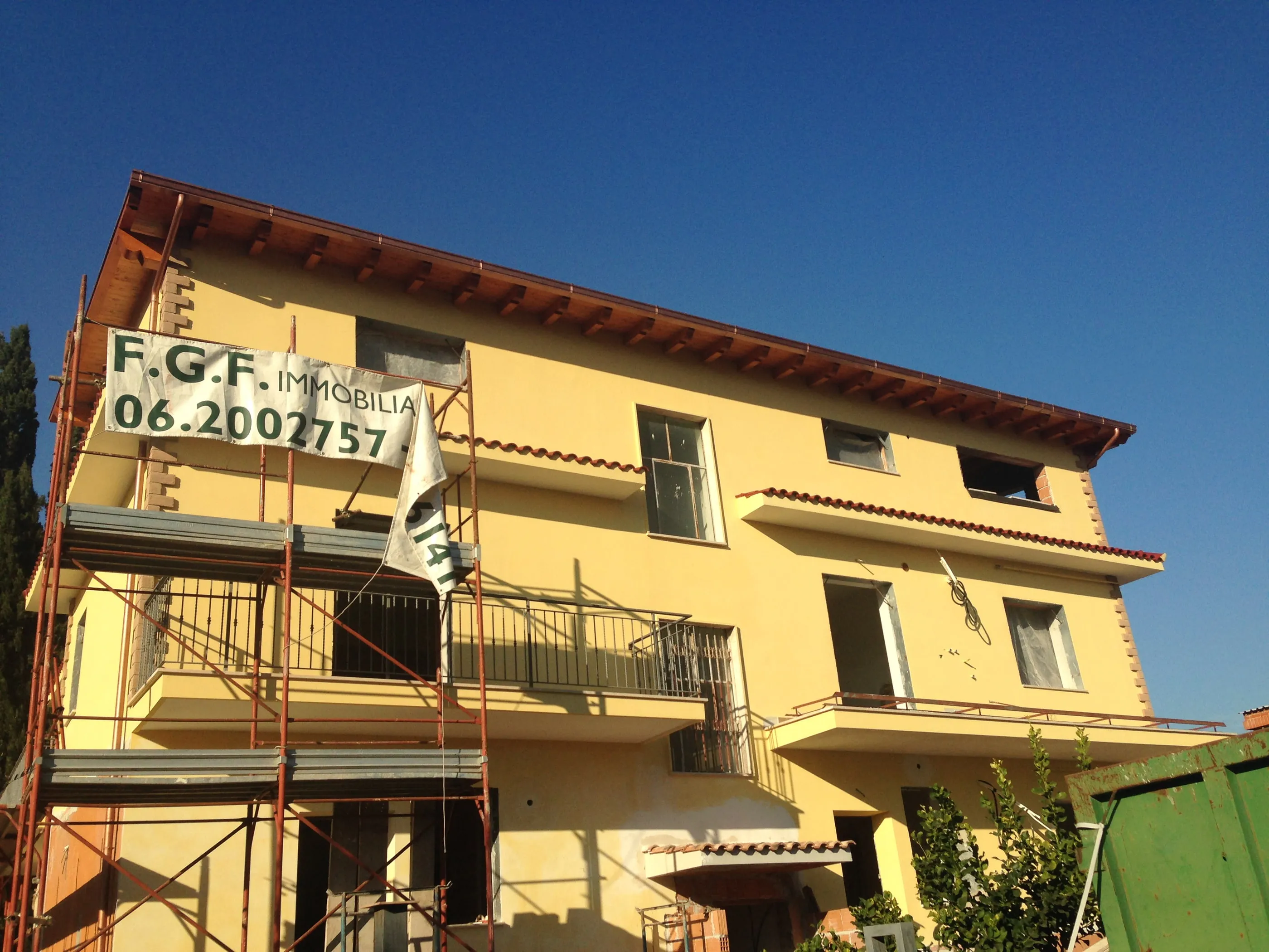 Palazzina in ristrutturazione con ponteggio montato sulla facciata e telo con il recapito di FGF Immobiliare