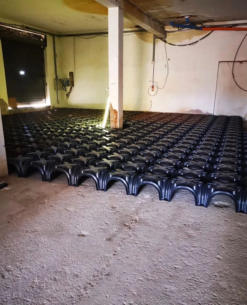Vespaio areato con cupole in plastica nera posate sul terreno di un piano terra, prima del getto